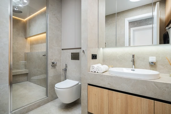 Salle de bain moderne avec vasque &agrave; poser ronde en c&eacute;ramique blanche sur plan de travail en bois massif