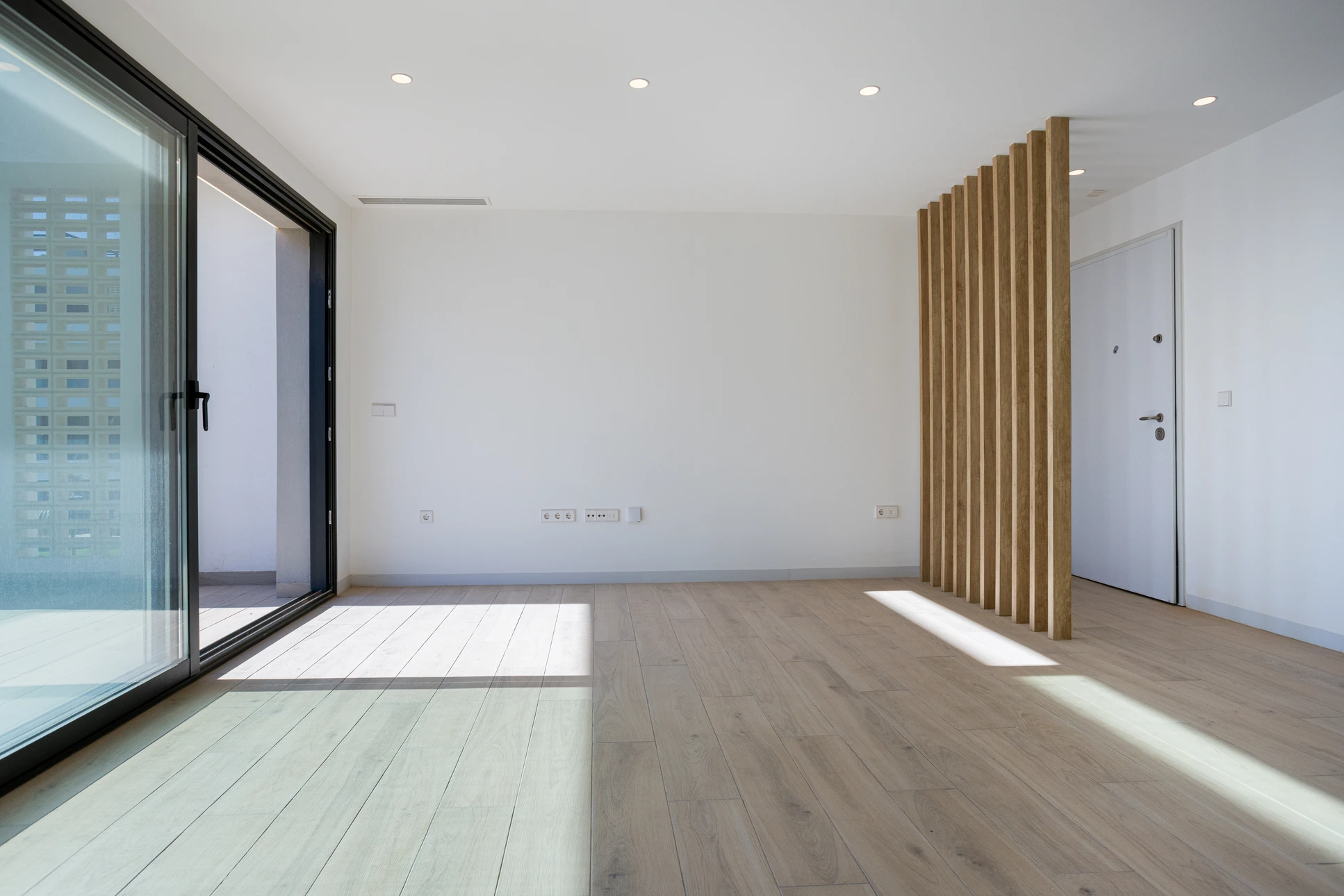 Ouvrier en bâtiment équipé d'un casque de sécurité jaune travaille à genoux sur un chantier intérieur, mesurant et positionnant des plaques de plâtre