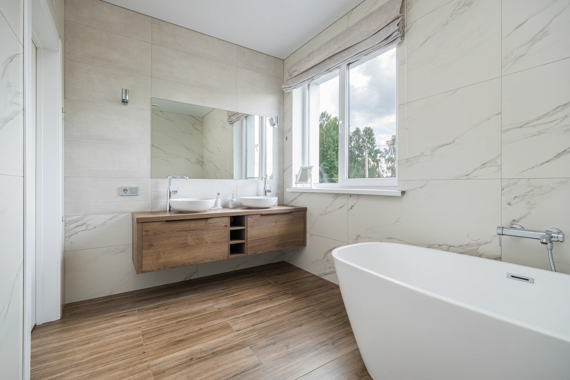 Photographie d'une salle de bain moderne en cours de finition ou récemment rénovée, mettant en avant un carrelage mural ou sol de haute qualité (style carrelage haut de gamme type Porcelanosa), avec des murs/sol fraîchement carrelés visibles et détails nets du travail de pose. La scène doit valoriser l'installation de carrelage comme élément central. Ambiance épurée et professionnelle, éclairage naturel ou professionnel mettant en valeur la qualité de la finition. Pas de texte, logo ou filigrane visible.
