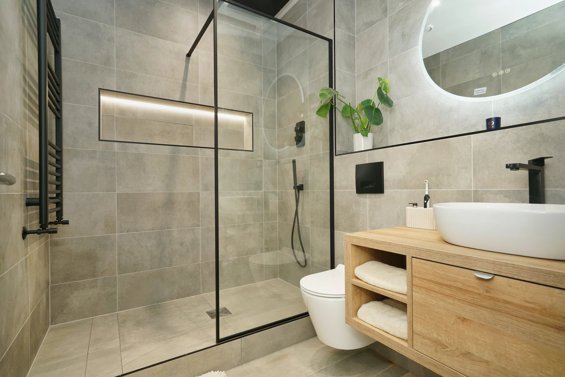 Salle de bain moderne avec douche à l'italienne vitrée, vasque double sur meuble suspendu en bois clair, robinetterie murale chromée
