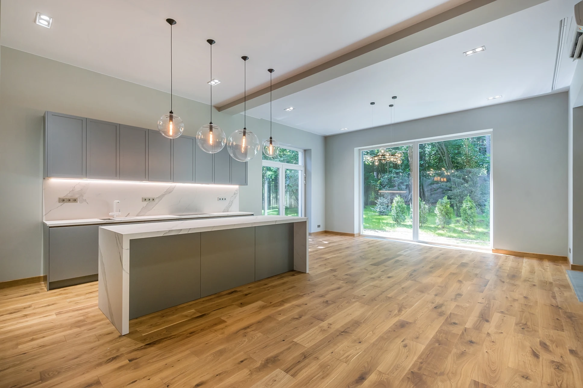 Photographe en intérieur d'une pièce en rénovation : gros plan sur les mains d'un artisan posant des lames de parquet massif ou contrecollé sur une sous-couche, avec un maillet et une cale de frappe. Le parquet est de belle qualité, légèrement clair ou miel. L'arrière-plan montre une pièce en cours de finition, sobre et moderne. La scène capture l'expertise et la précision du travail d'installation professionnelle.